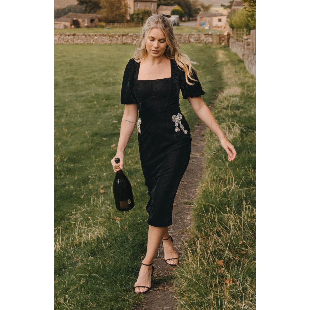 Woman wearing a Hope &amp; Ivy black dress with floral embellishments on a white background