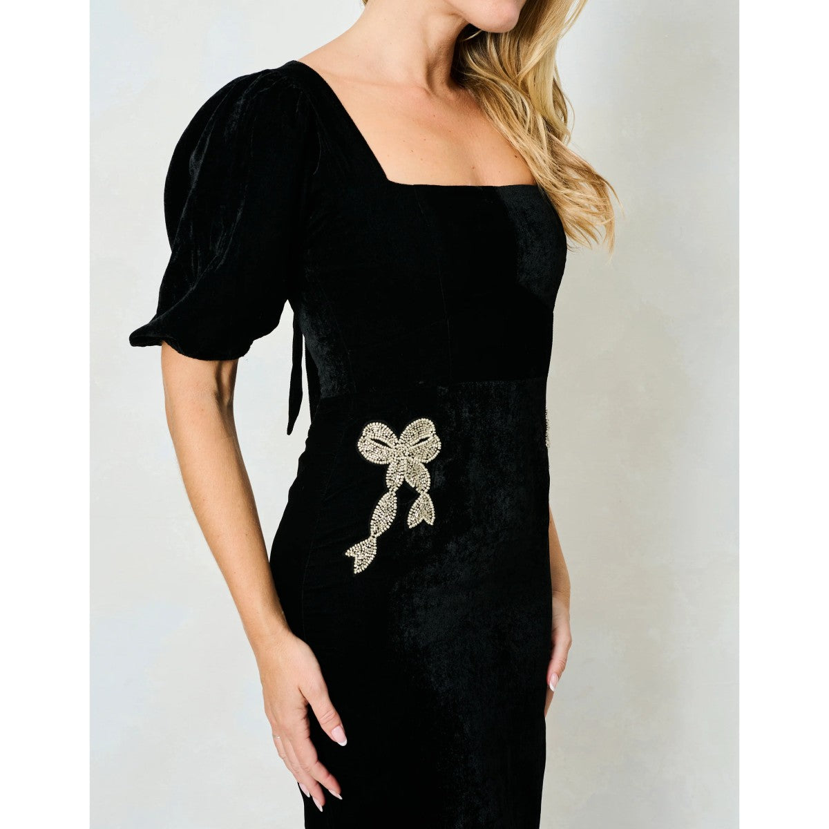 Woman wearing a Hope & Ivy black dress with floral embellishments on a white background