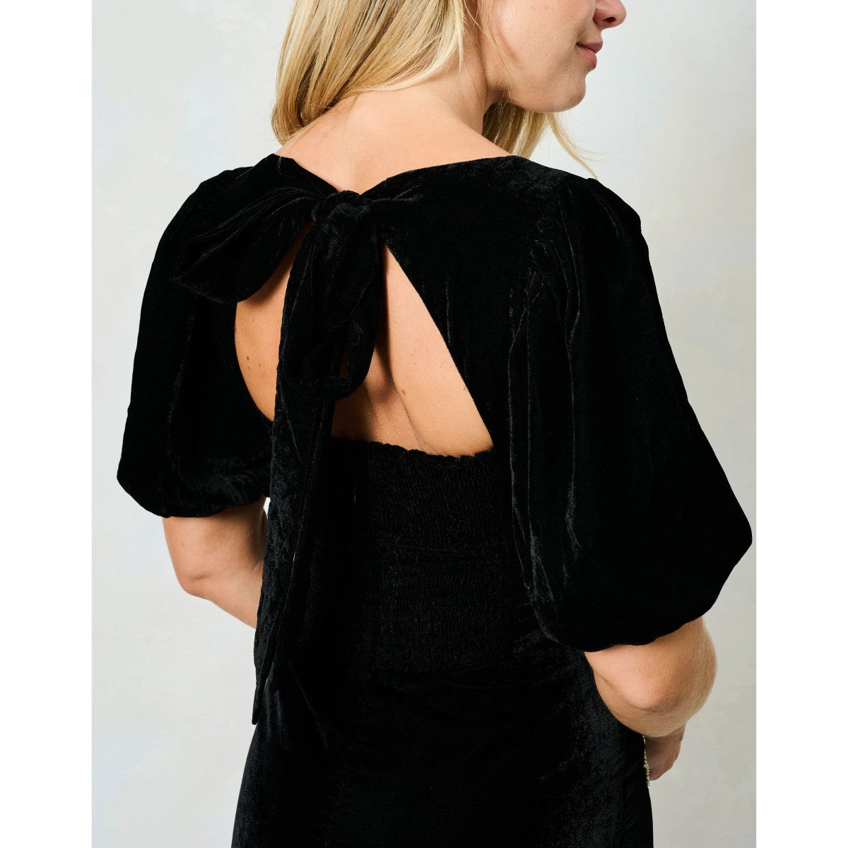 Woman wearing a Hope &amp; Ivy black dress with floral embellishments on a white background