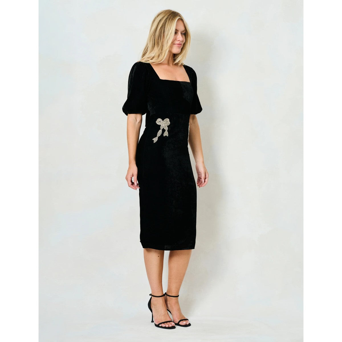 Woman wearing a Hope & Ivy black dress with floral embellishments on a white background