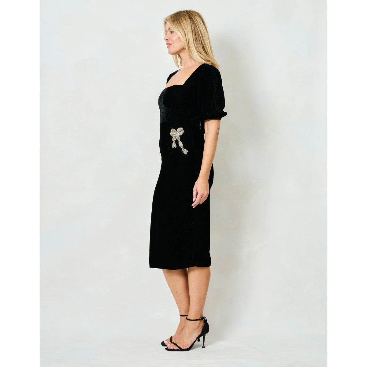 Woman wearing a Hope & Ivy black dress with floral embellishments on a white background