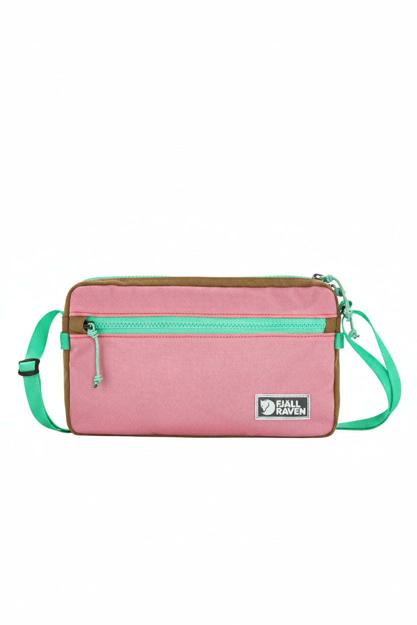 Pink crossbody bag with green straps and visible brand logo on a white background