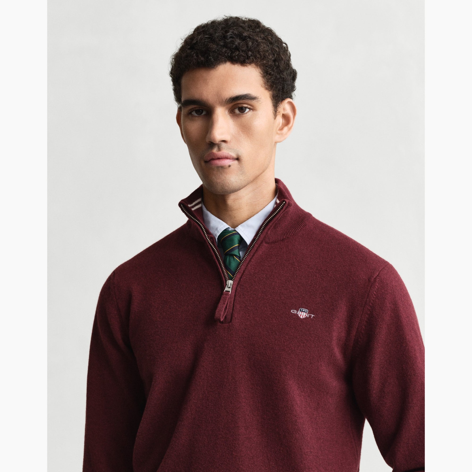 Man wearing a burgundy GANT  sweater with a white background