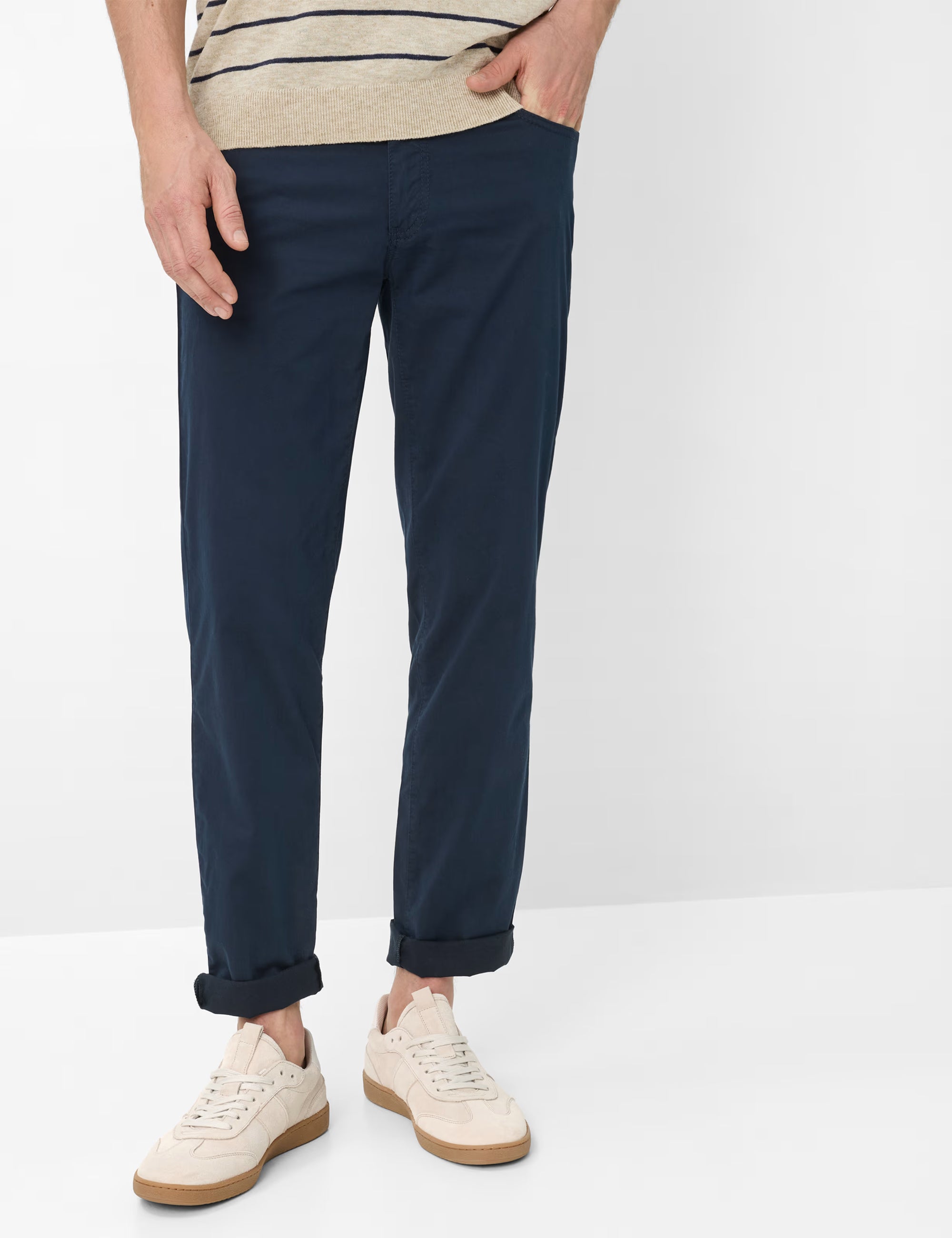 Person wearing navy pants and white sneakers on a plain background