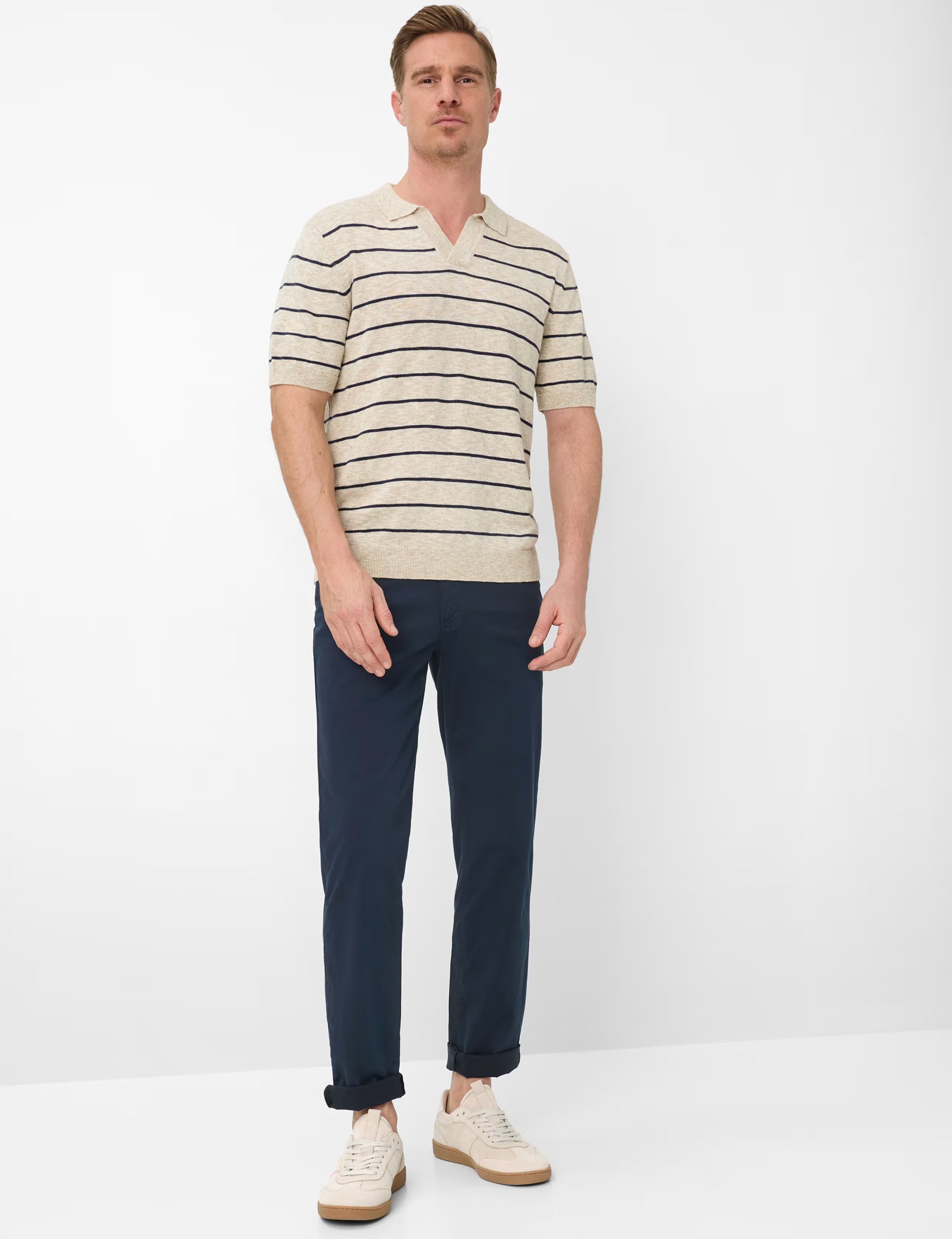 Man wearing a striped shirt and dark pants on a white background