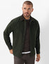 A man wearing an Brax pine green button-up overshirt jacket over a dark brown sweater and dark trousers, photographed against a clean white studio background.