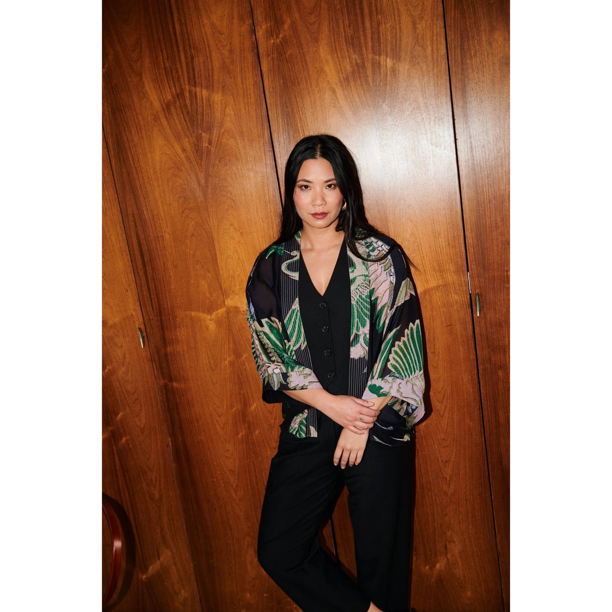 Woman wearing a patterned jacket against a wooden wall