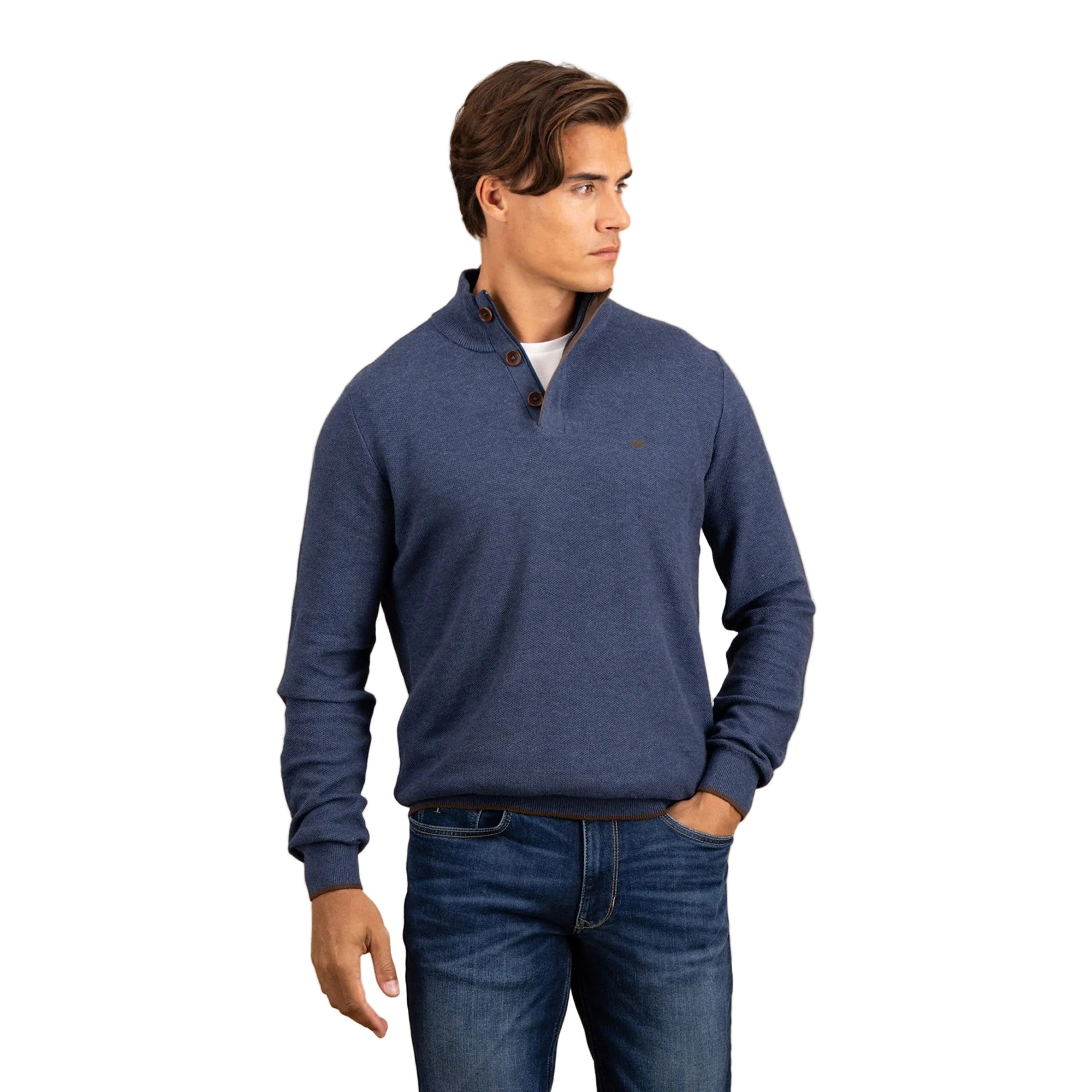 Man wearing a blue sweater and jeans against a beige background