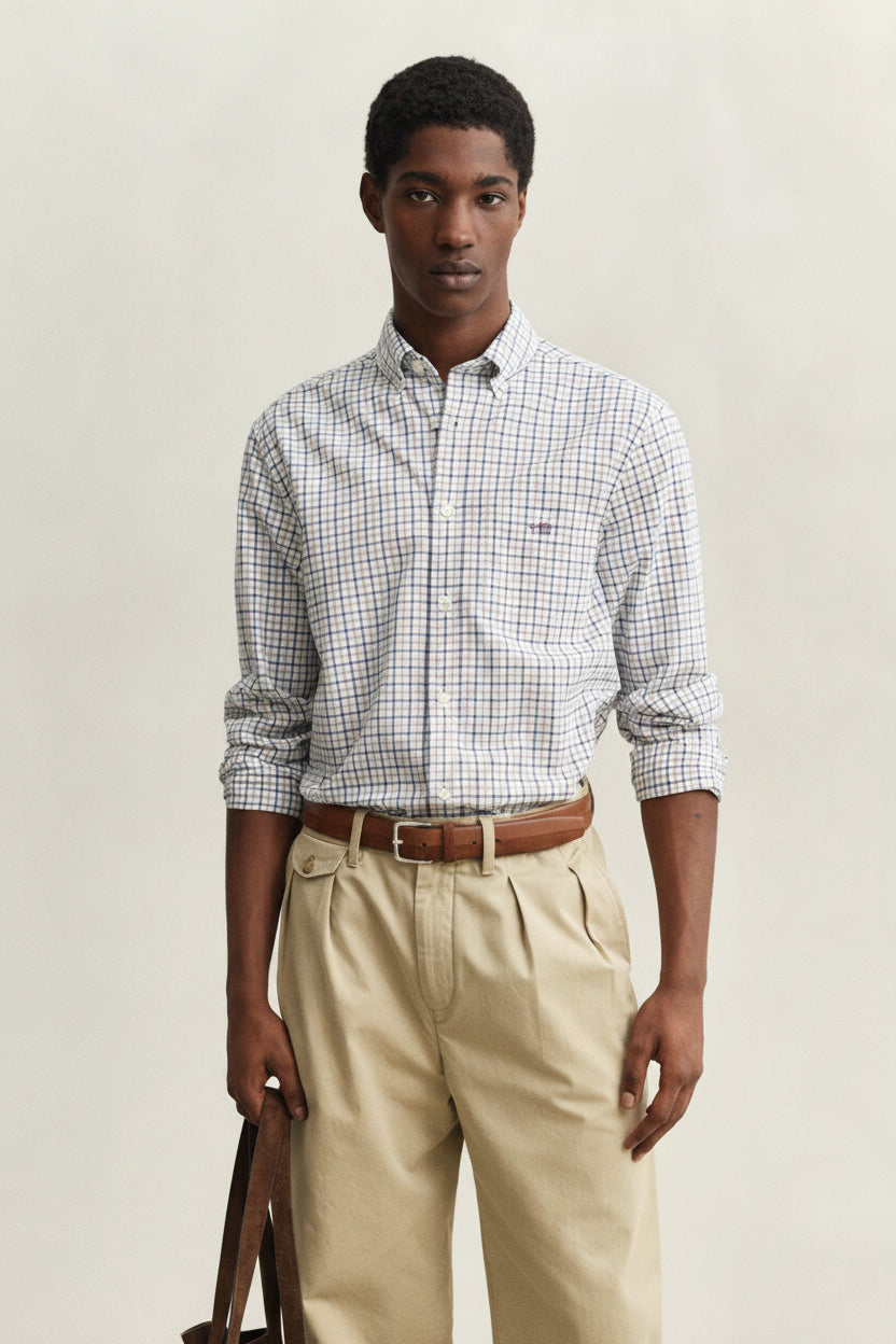 Man wearing a checkered shirt and beige pants against a plain background