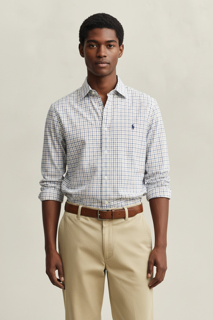 Man wearing a checkered shirt and beige pants against a plain background