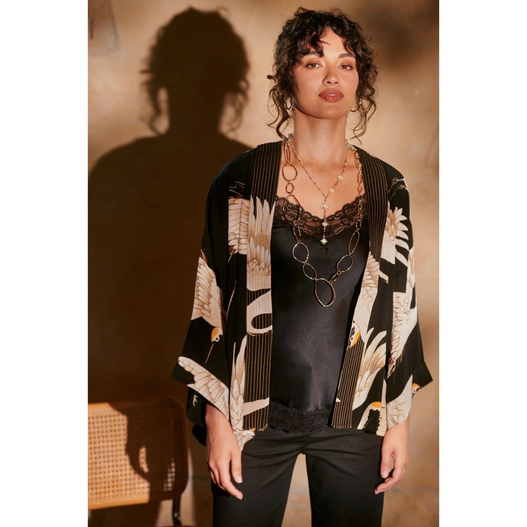Woman wearing a patterned kimono over a black top against a warm-toned background