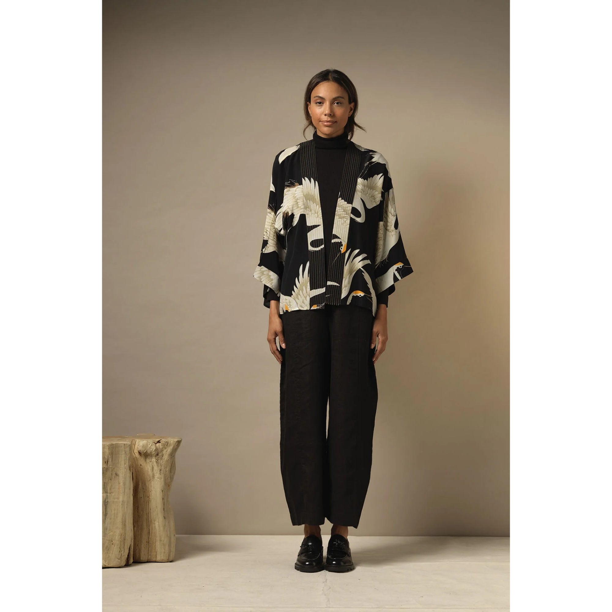 Woman wearing a black and white patterned kimono against a beige background