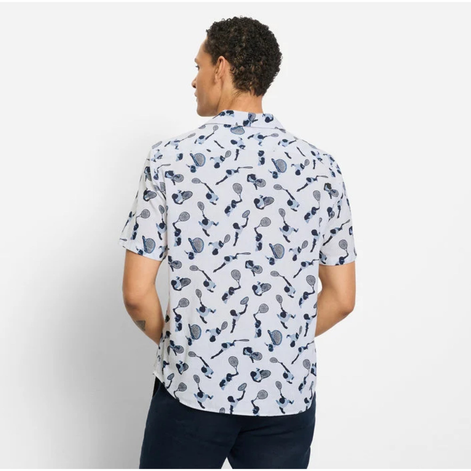 Person wearing a white shirt with black pattern on a plain background