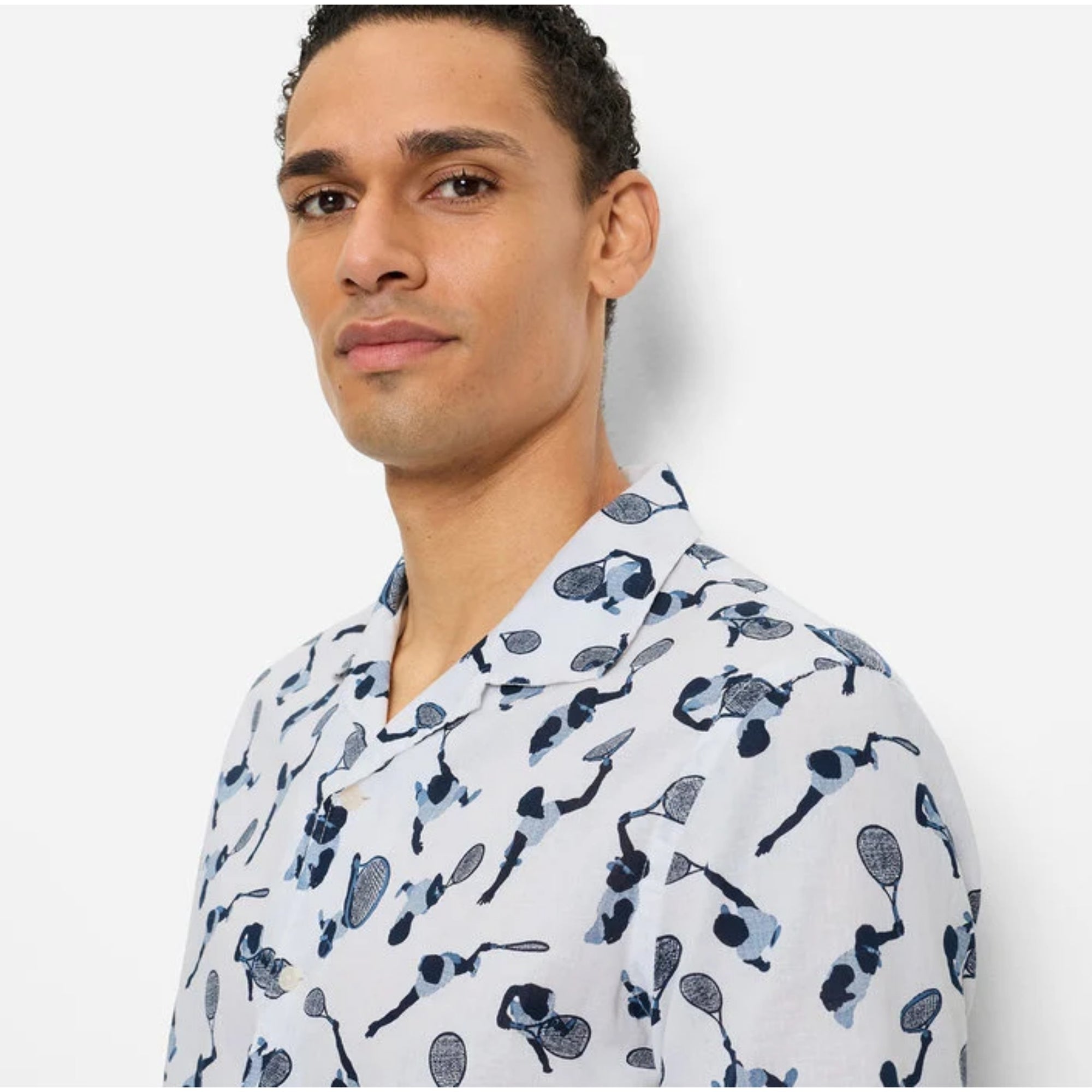 Man wearing a white shirt with black pattern against a plain background