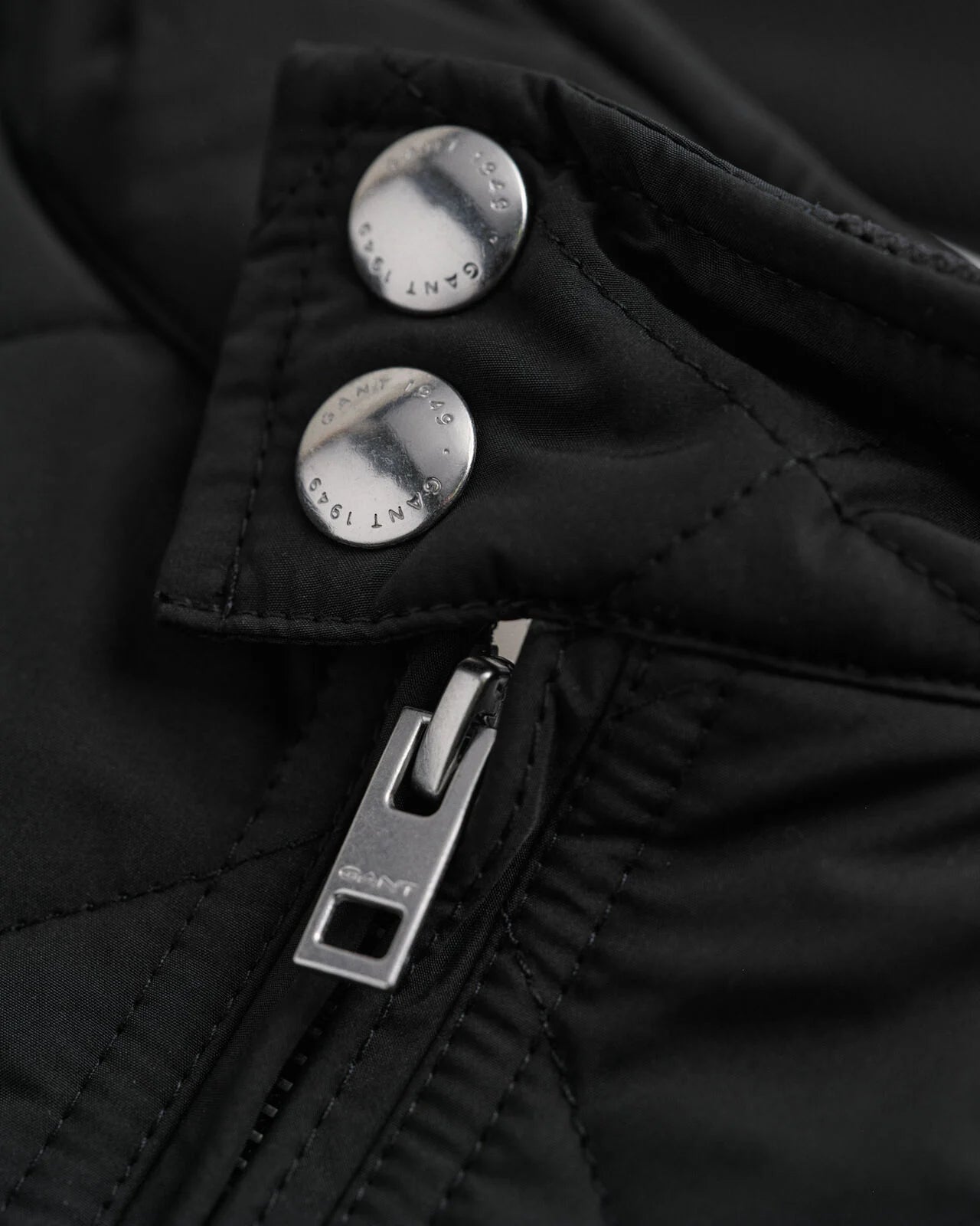 Close-up of a black jacket with silver buttons and zipper