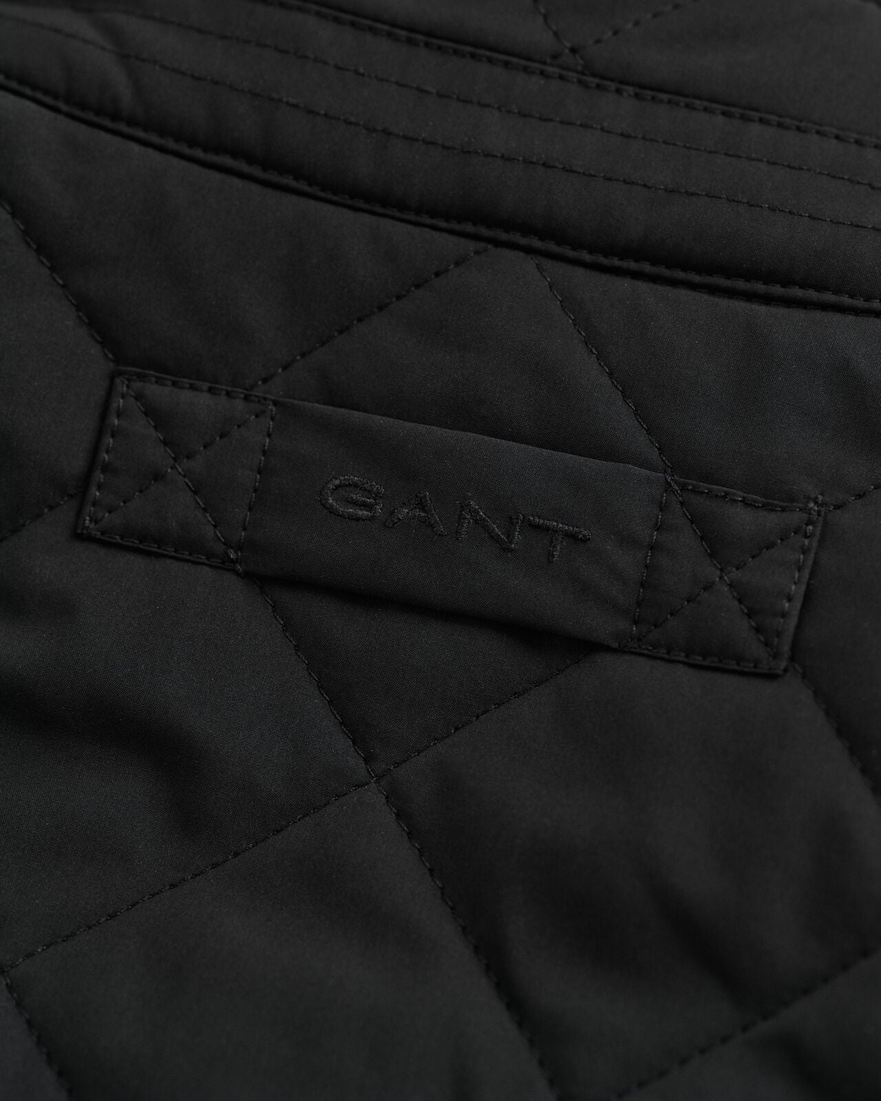 Close-up of a black quilted jacket with GANT logo