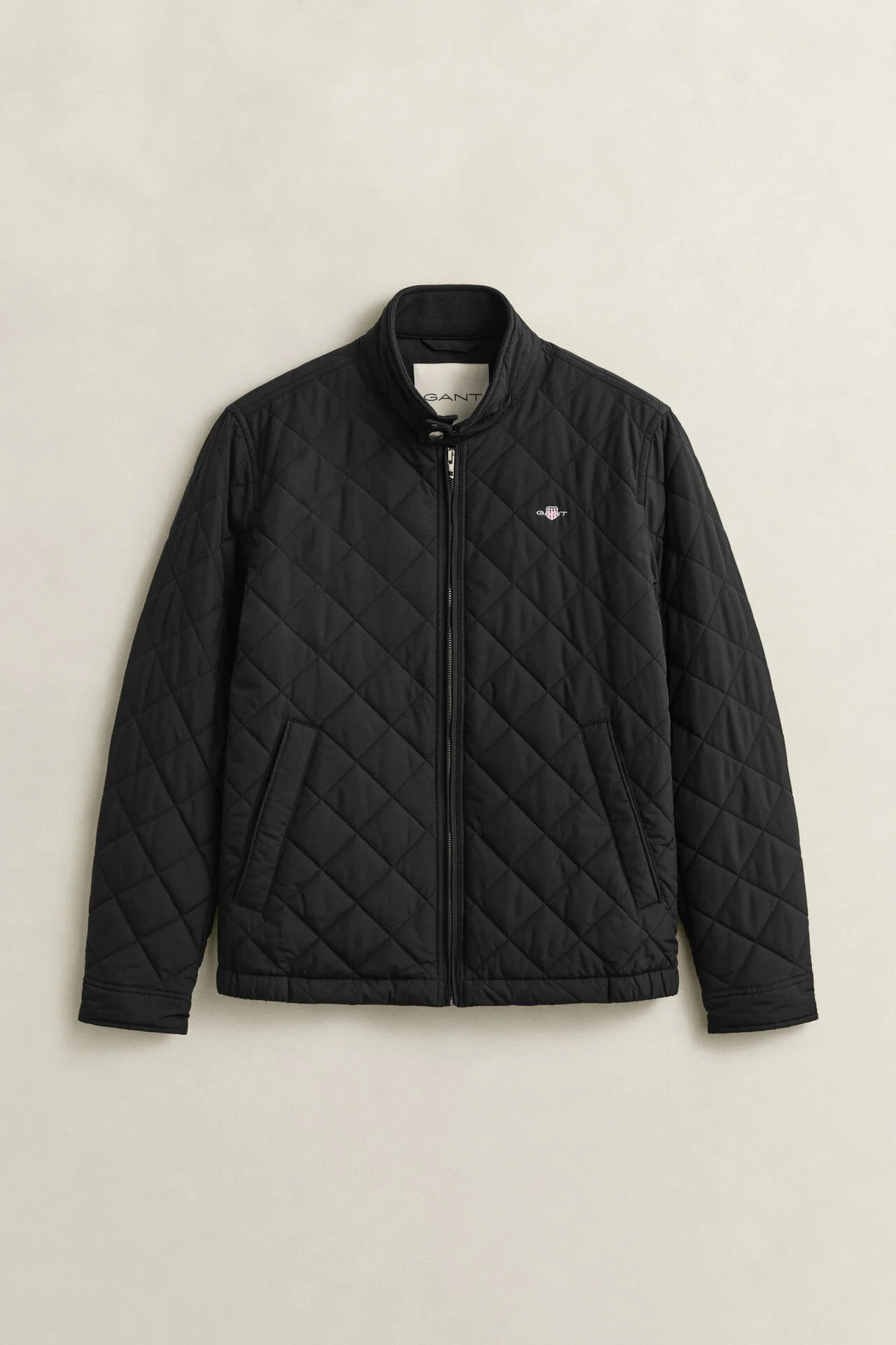 Black quilted jacket on a beige background