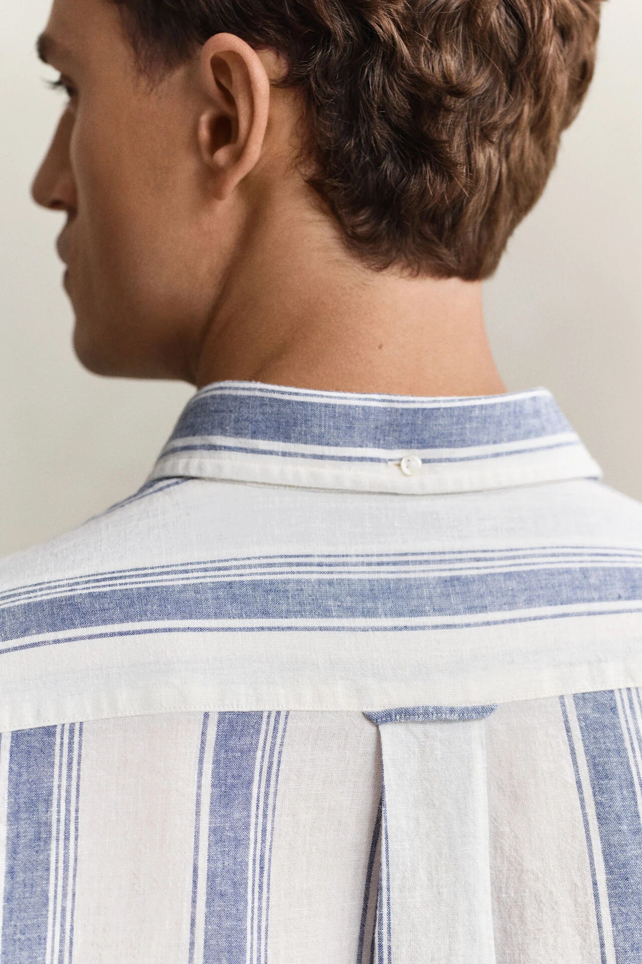 Close-up of a person wearing a striped shirt with a neutral background