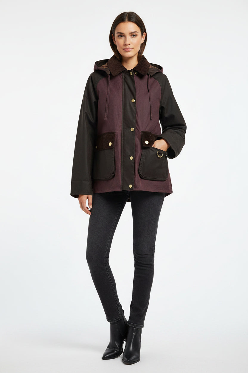 A Barbour hooded jacket with a dark purple body, black sleeves, and a dark brown faux-fur collar and pocket flaps, featuring gold-tone hardware.