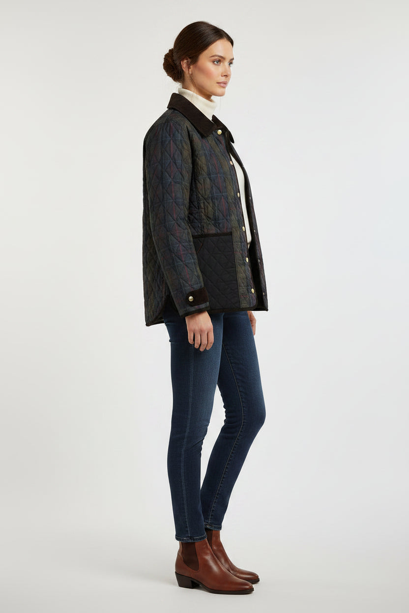 A woman modeling a dark navy quilted jacket with brown faux-fur trim, worn over a cream turtleneck and dark blue skinny jeans, against a light gray studio background.
